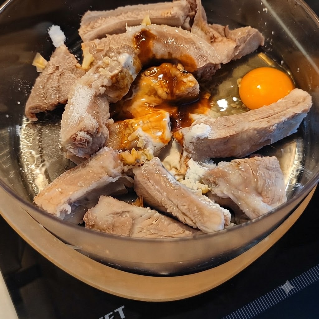Costillas de cerdo marinándose con varias salsas y un huevo agrietado en un bol.