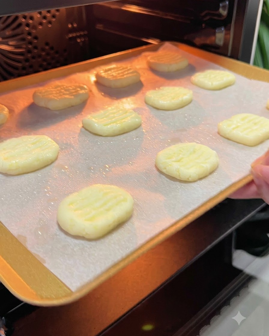 Una bandeja para hornear con tortitas de patata siendo deslizada hacia el interior brillante de un horno precalentado.