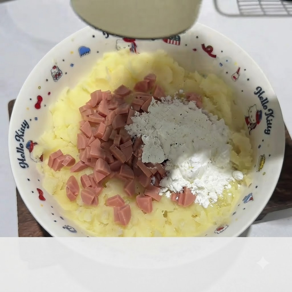 Mano con guante amasando la mezcla de puré de patata con jamón y fécula hasta formar una masa dentro del bol blanco.