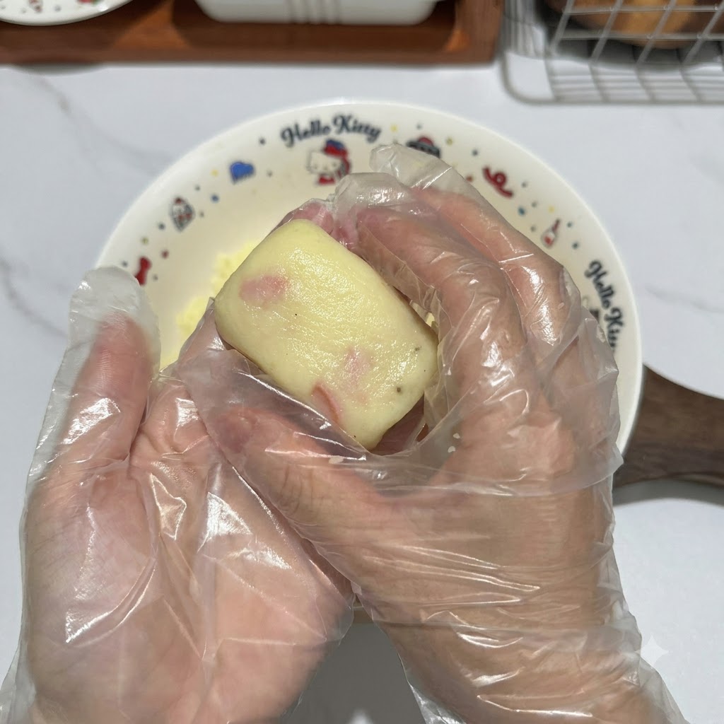 Manos enguantadas dando forma a una porción de masa de patata para convertirla en una ordenada tortita rectangular.