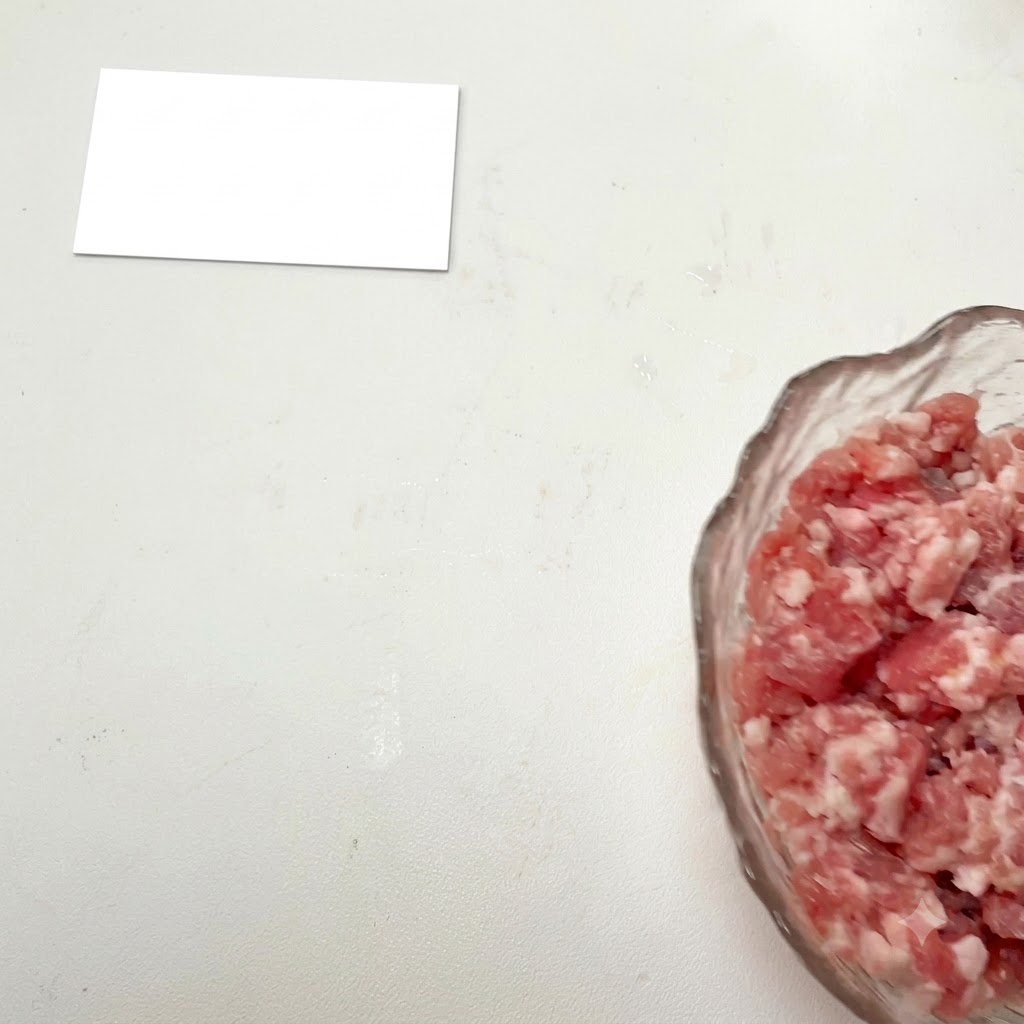 Carne picada en un bol de cristal con los condimentos añadidos.