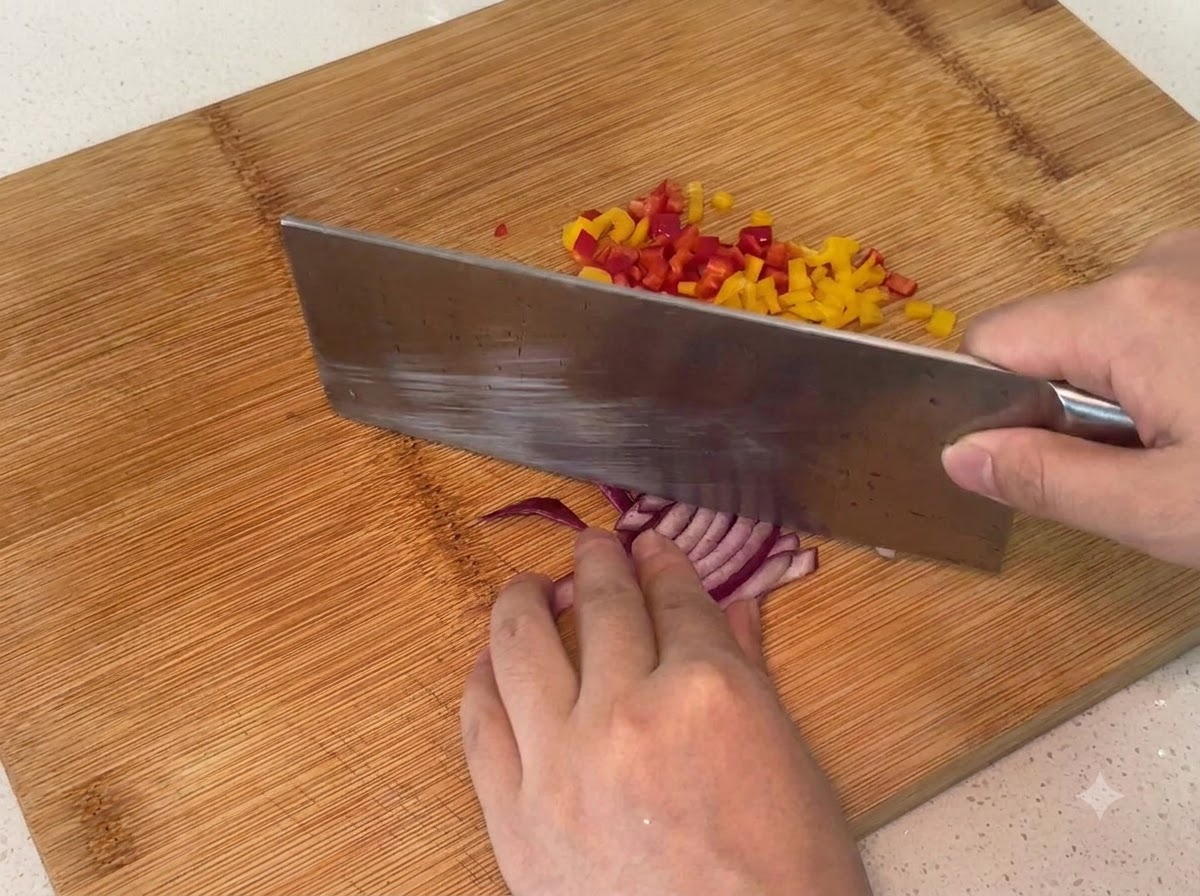 Cebolla morada siendo picada en trozos pequeños sobre una tabla de cortar de madera.