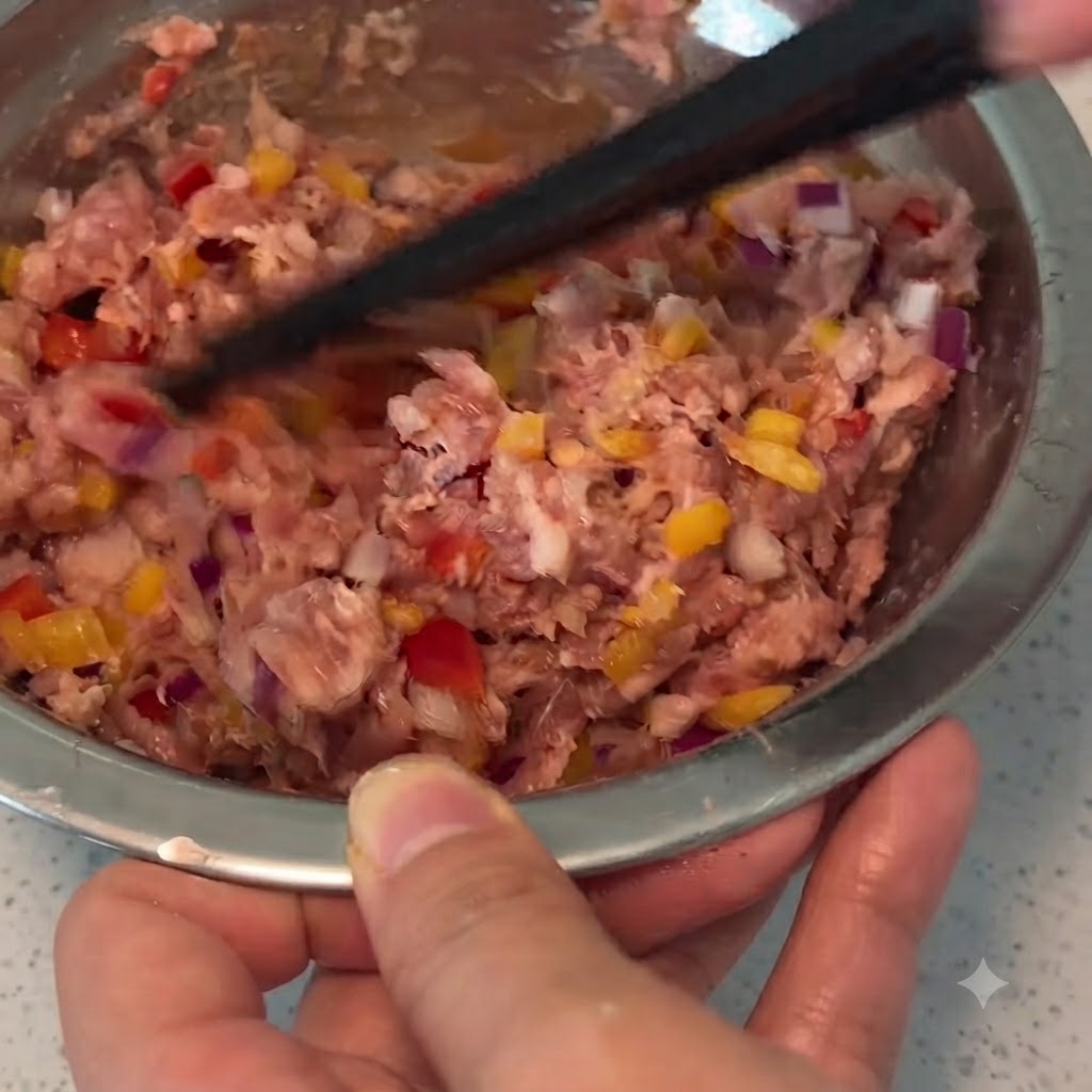 Un par de palillos mezclando carne de cerdo picada, verduras y condimentos juntos dentro de un bol de metal.