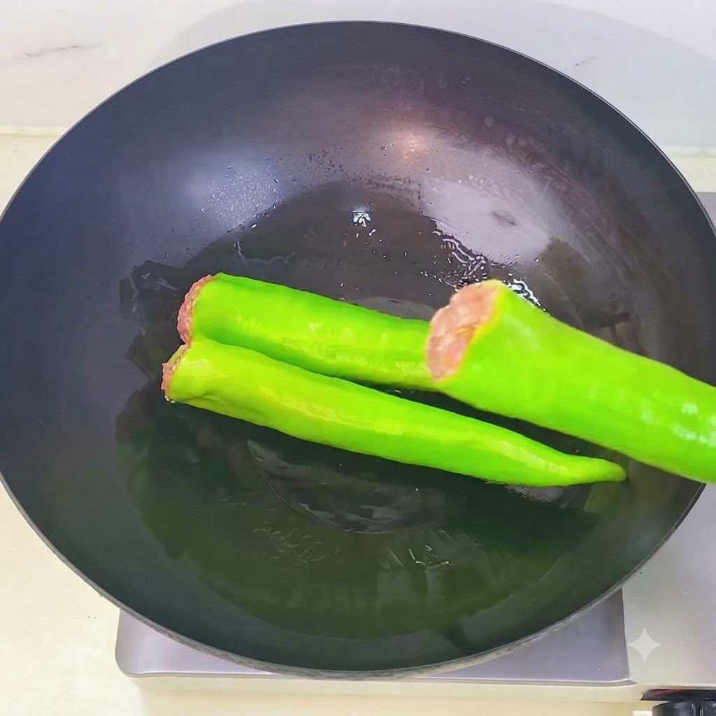 Pimientos verdes rellenos colocándose en secuencia dentro de un wok caliente con aceite.
