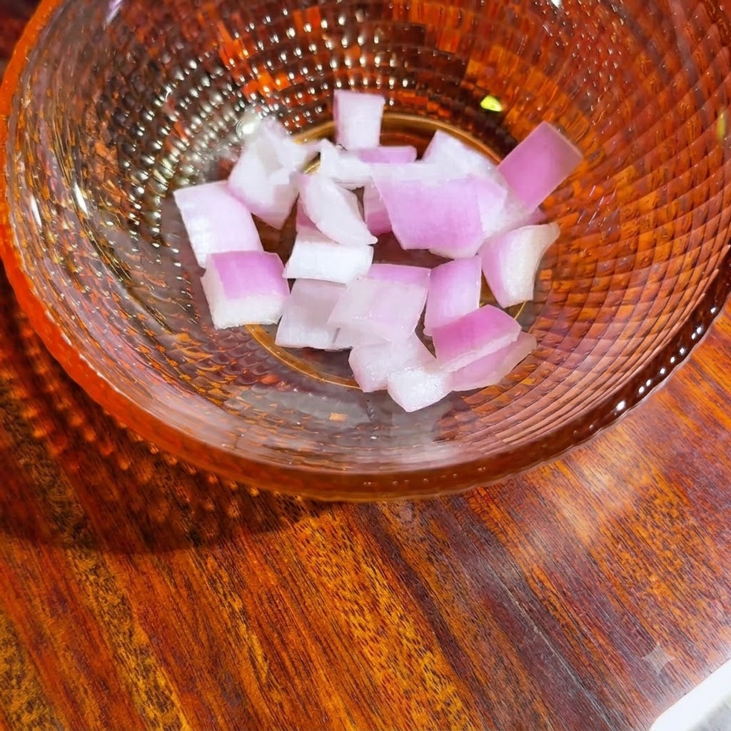 Un tazón de vidrio que contiene trozos de cebolla morada recién picados listos para la salsa de aguacate.