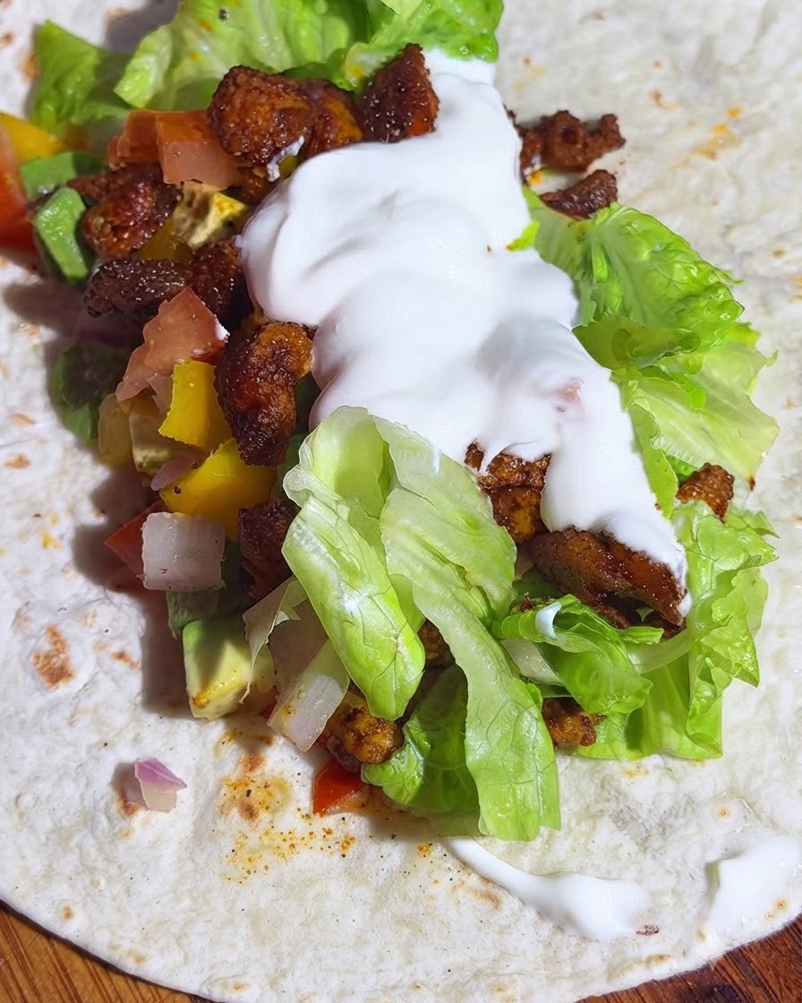 Una tortilla integral con capas de lechuga, salsa de aguacate, pollo y una cucharada de yogur.