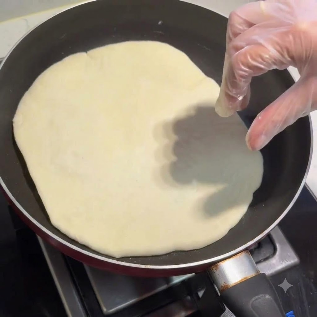 Una tortilla cocinándose en una sartén con una mano con guante ajustándola.