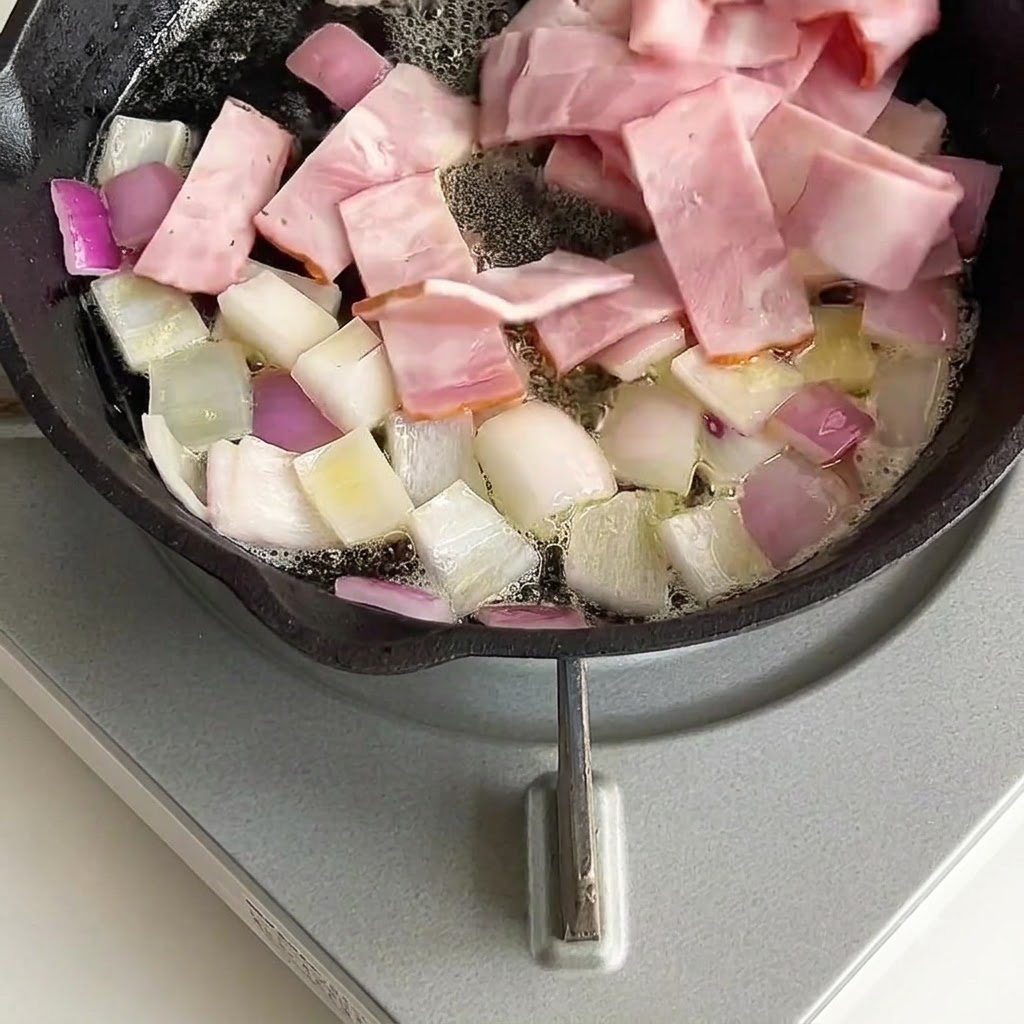 Trozos de tocino mezclados y salteados con cebollas en la sartén.