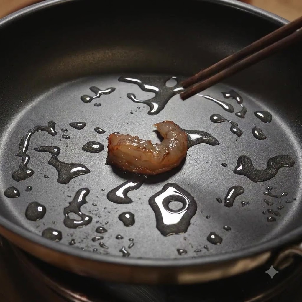 Una sola pieza de camarón siendo volteada con palillos en una sartén aceitada.