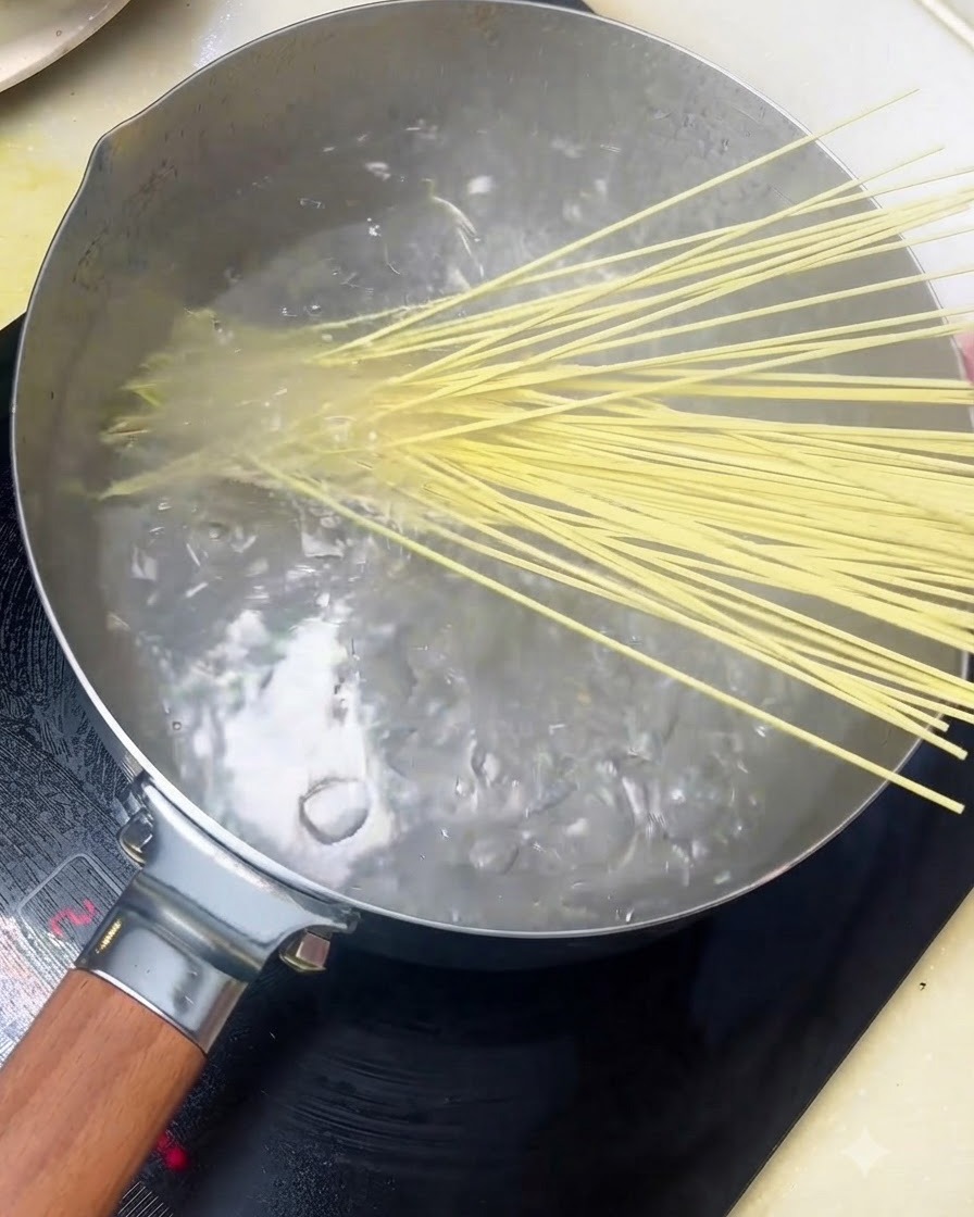 Fideos alcalinos introduciéndose en una olla con agua hirviendo.
