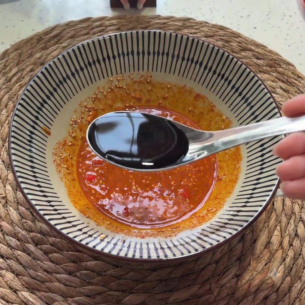 Salsa de soja clara vertida desde una cuchara en la mezcla de salsa sazonada.