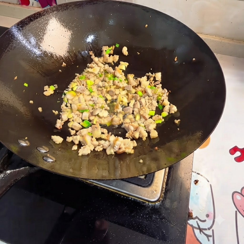 Carne picada y aromáticos salteándose en un wok.