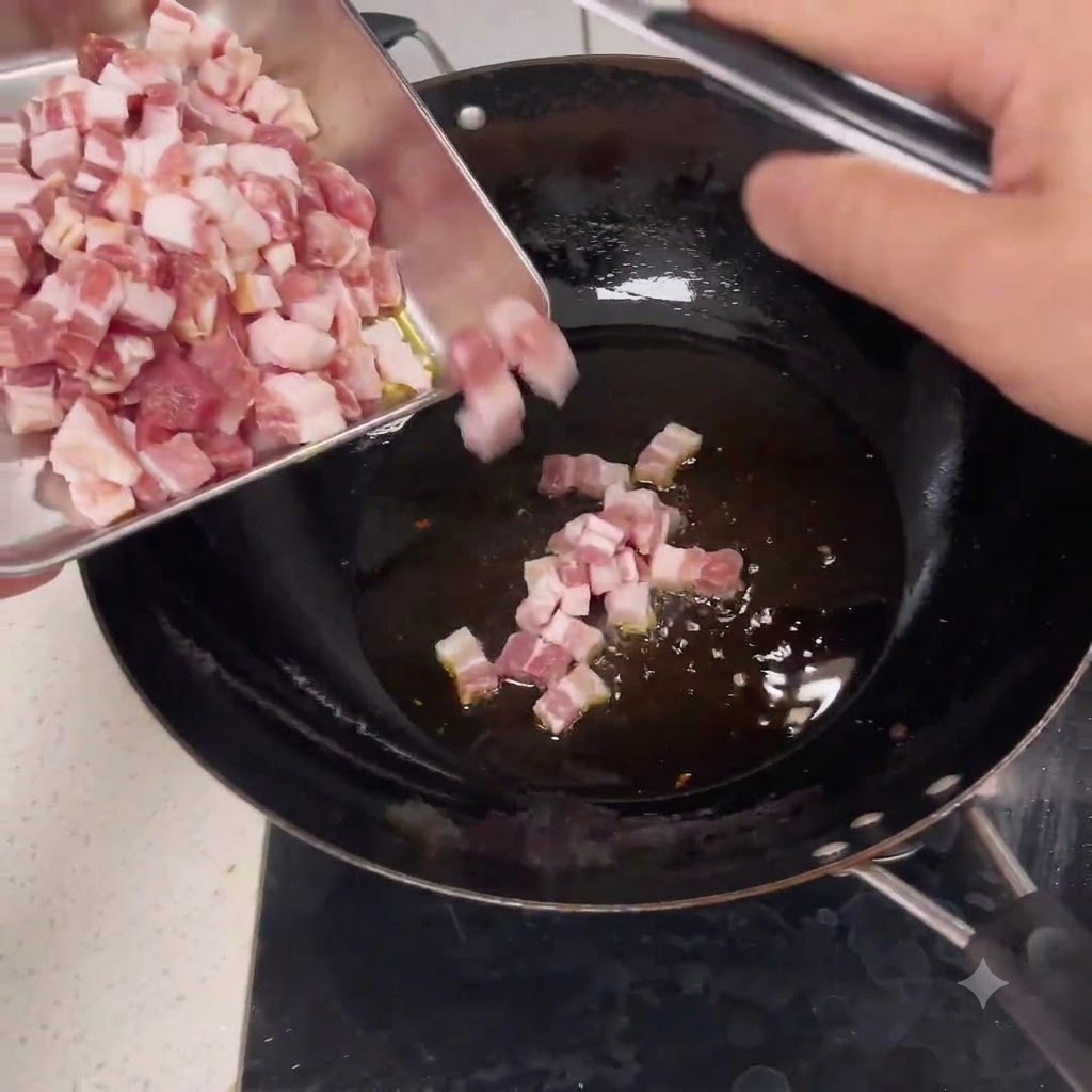 Trozos de cerdo picado crudo deslizándose desde una bandeja de metal hacia un wok con aceite caliente.