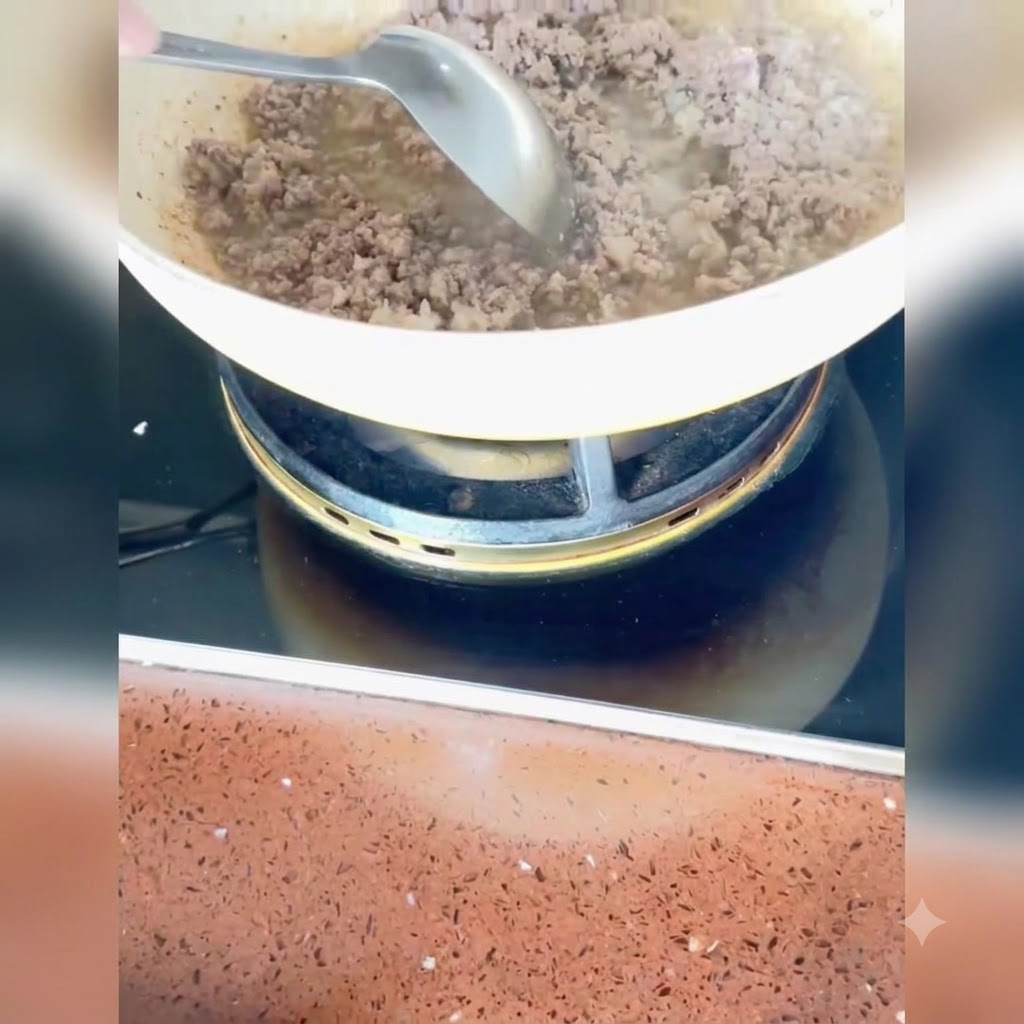 Cebolletas picadas, jengibre y ajo siendo revueltos con la carne cocida en la sartén.