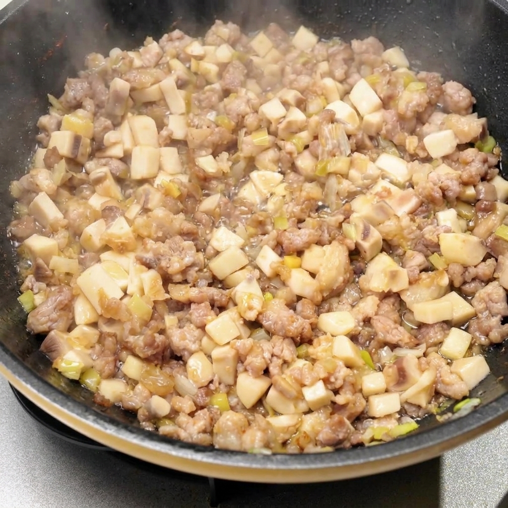 Varios condimentos líquidos y salsas siendo vertidos en la sartén con la mezcla de carne y champiñones.