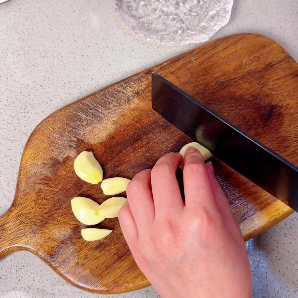Dientes de ajo dispuestos en una tabla de picar de madera listos para ser picados.