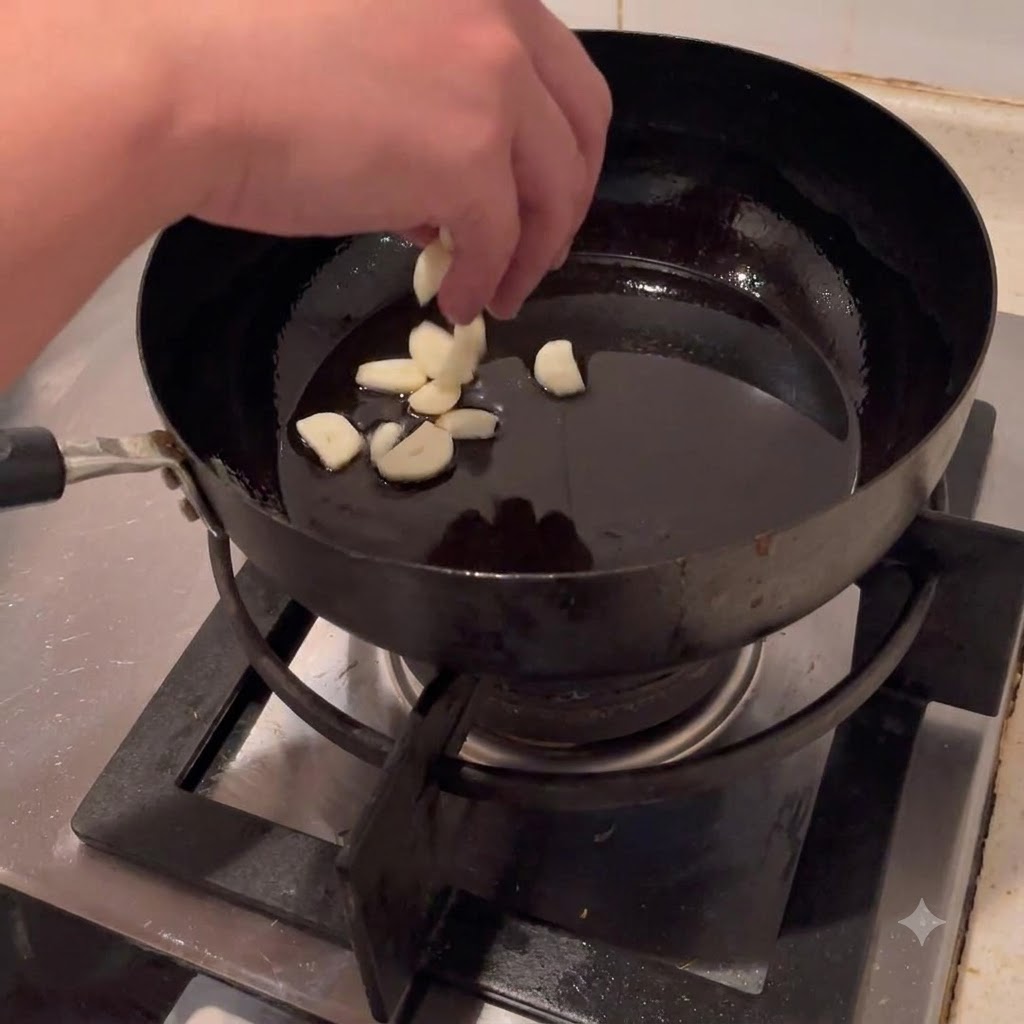 Rodajas de ajo siendo arrojadas al aceite caliente en un wok.