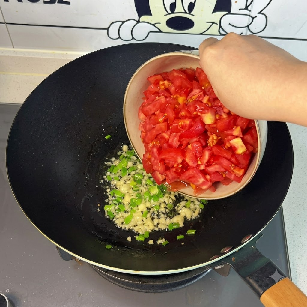 Tomates rojos frescos recién picados cayendo desde un cuenco hacia el wok.
