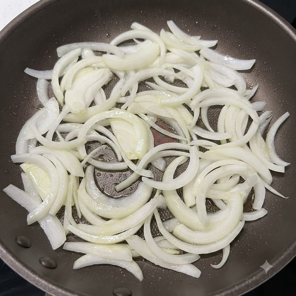 Tiras de cebolla siendo salteadas en una sartén caliente hasta que los bordes estén ligeramente dorados.