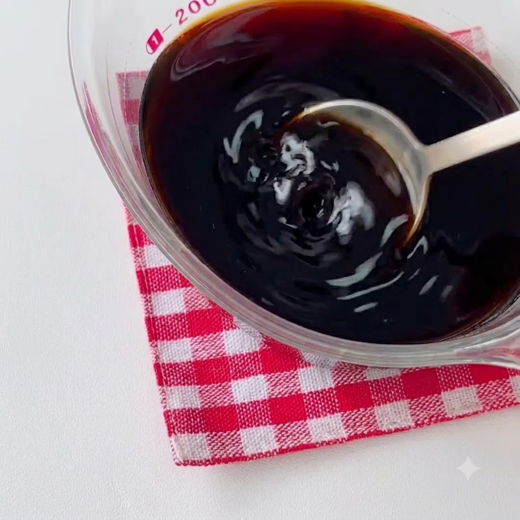 Trozos de pollo marinados friendose en una sartén caliente con aceite y siendo removidos con una cuchara.