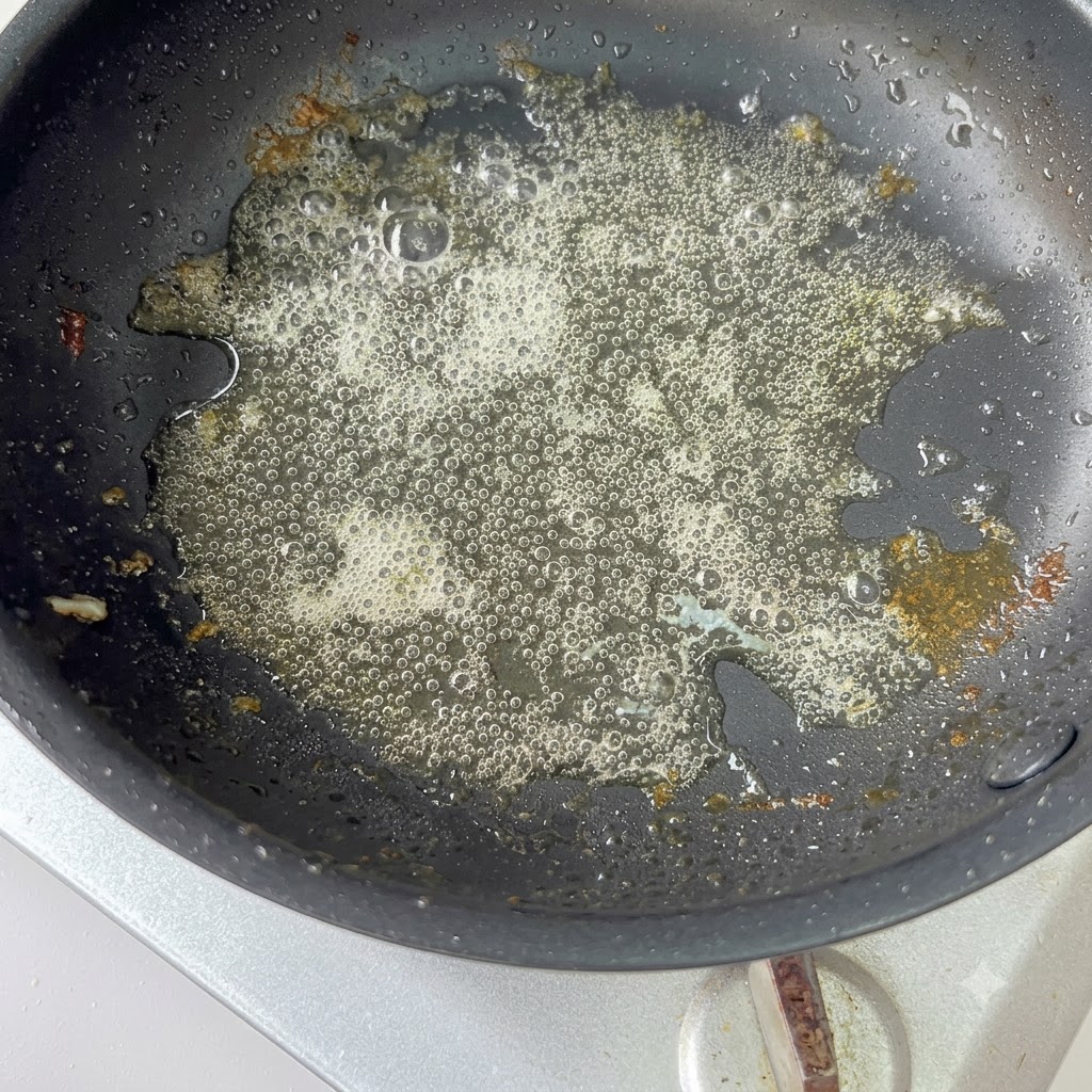 Cebollas moradas cortadas siendo salteadas en una sartén caliente con el aceite restante.