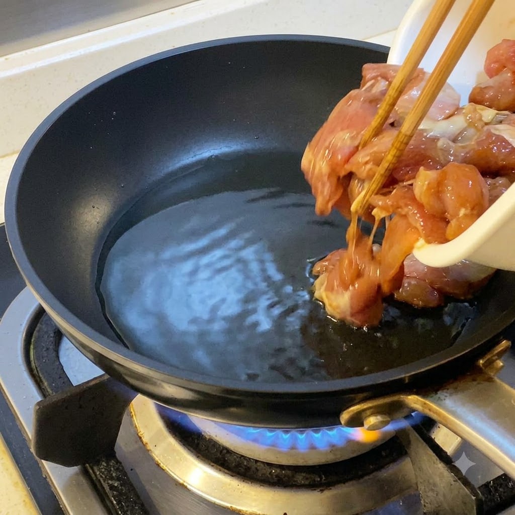 Trozos de pollo marinado agregados con palillos en una sartén caliente con aceite.