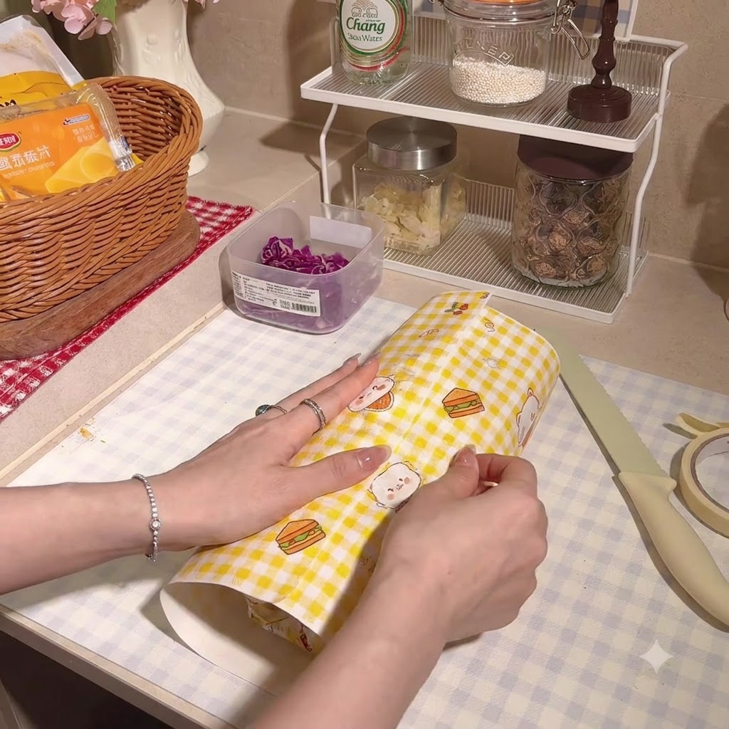 El sándwich grueso envuelto de forma segura dentro de papel pergamino a cuadros.