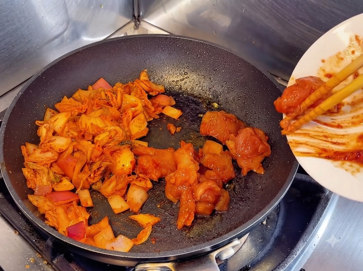 Usando palillos para deslizar trozos de pollo crudo marinado desde un plato blanco a una sartén junto al kimchi y las cebollas salteadas.