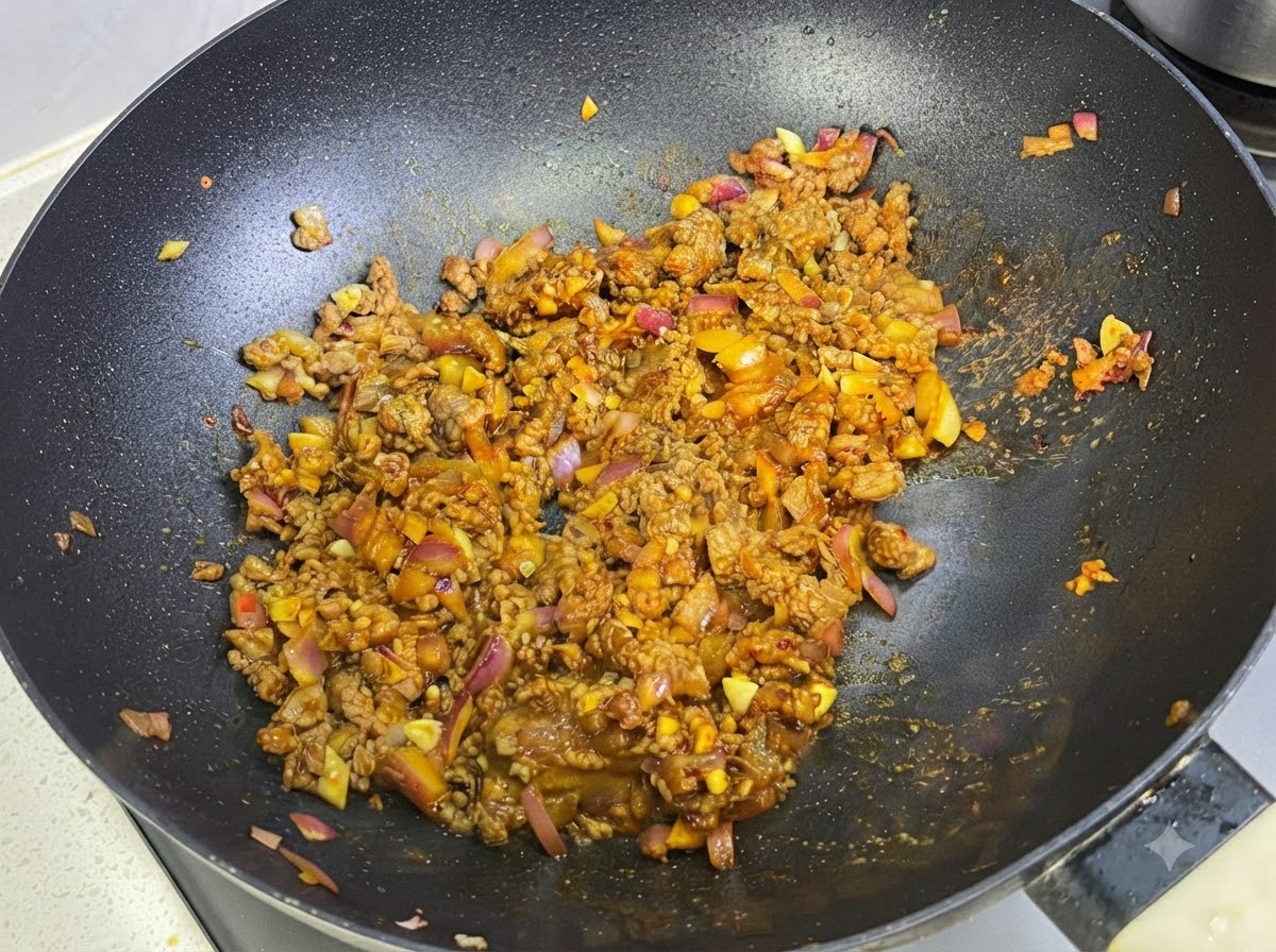 Leche siendo incorporada en la salsa de curry y carne dentro de la sartén.