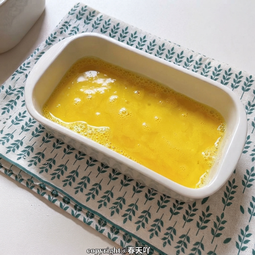 Un plato de cerámica blanca lleno de huevos batidos de color amarillo dorado.