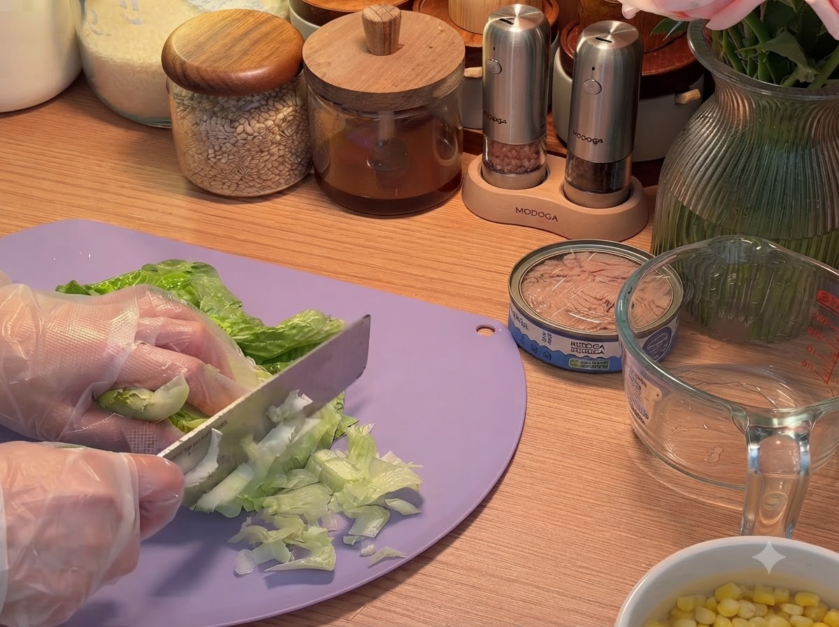 Hojas de lechuga verde siendo cortadas en tiras sobre una tabla de cortar con un cuchillo.