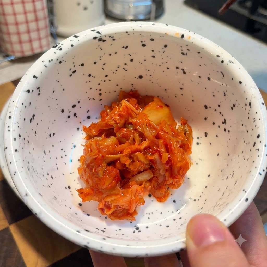 Un bol blanco con motas lleno de una porción de kimchi picado de color rojo brillante.