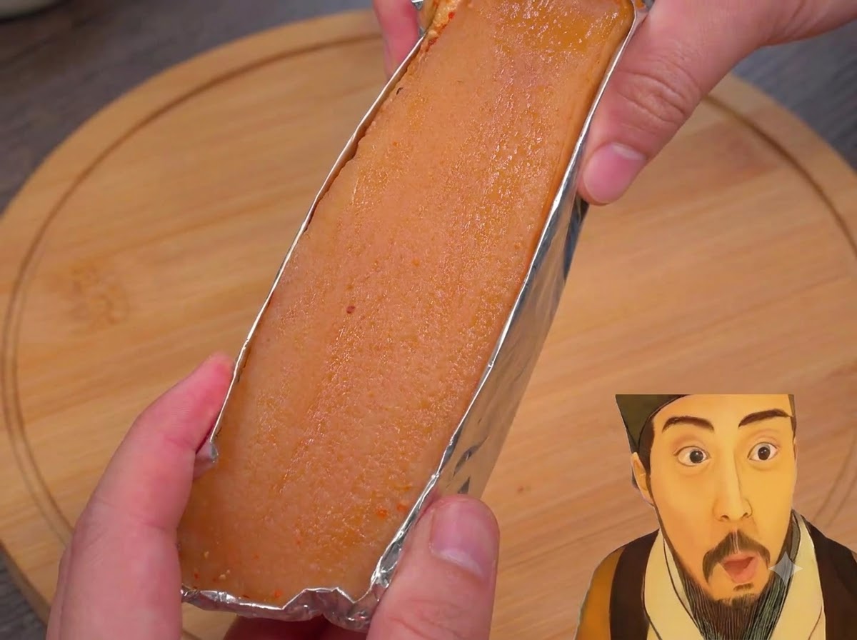 Primer plano de tiras de panceta envueltas en aluminio siendo pinceladas con vinagre blanco.