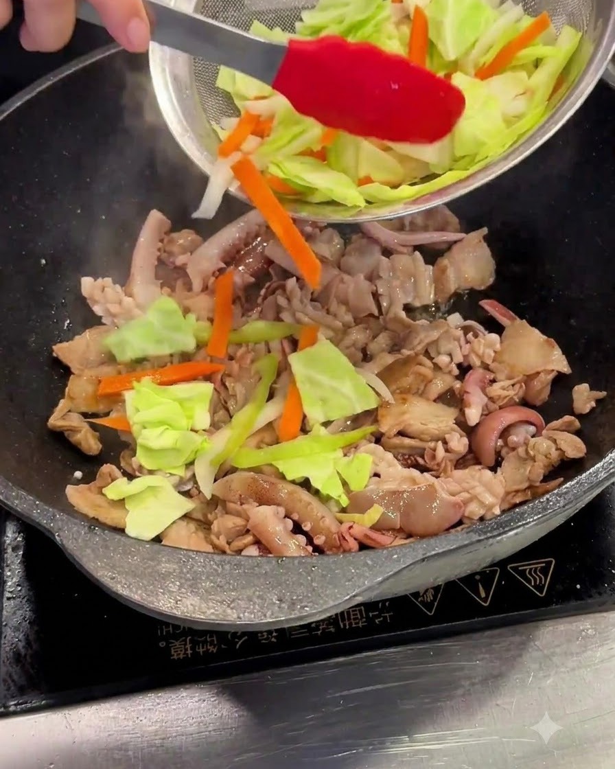 Repollo y zanahorias cortadas siendo añadidos desde un colador de malla hacia el wok.