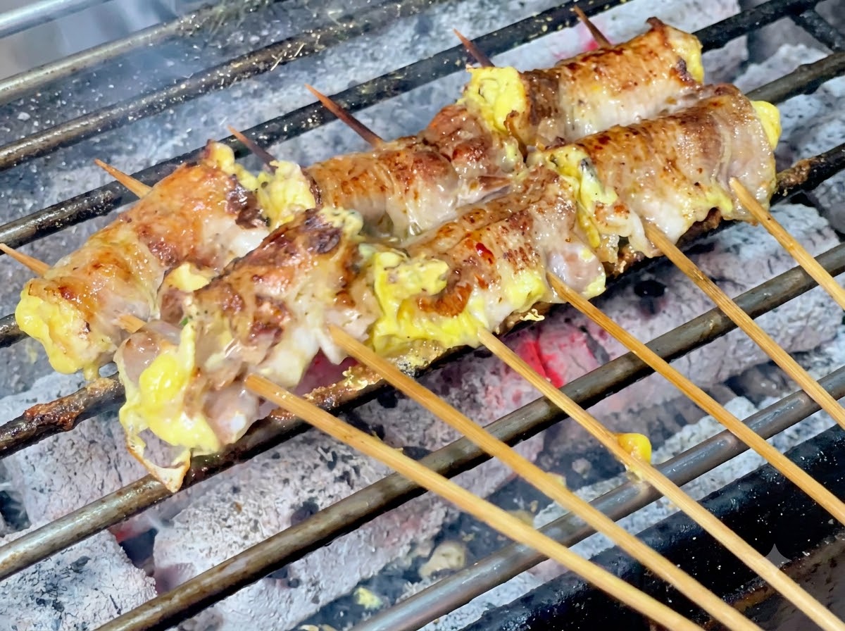 Chile en polvo cayendo sobre los rollitos de carne en la parrilla de carbón.