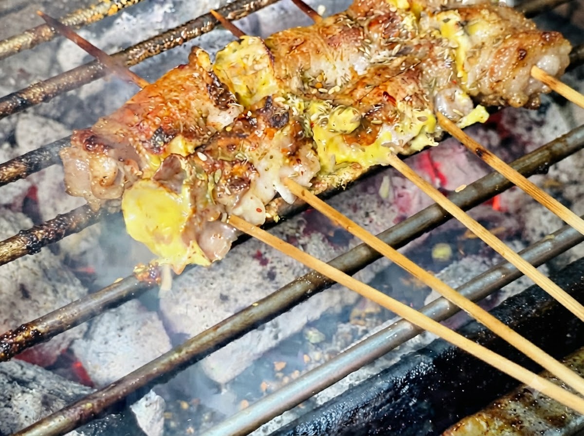 Semillas de sésamo siendo espolvoreadas sobre los rollitos de carne recién asados.