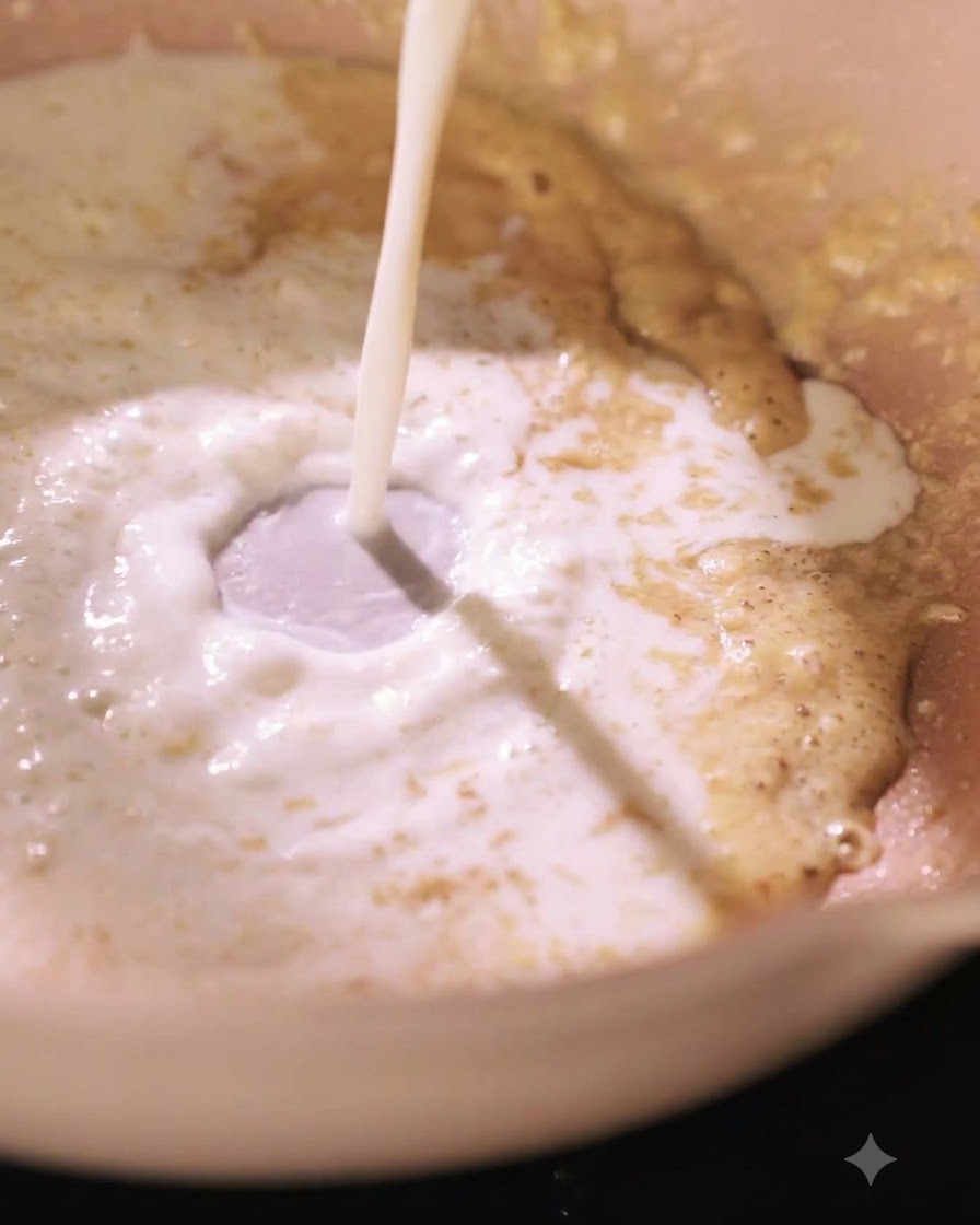Leche siendo vertida en una sartén con una mezcla de roux, creando un remolino.