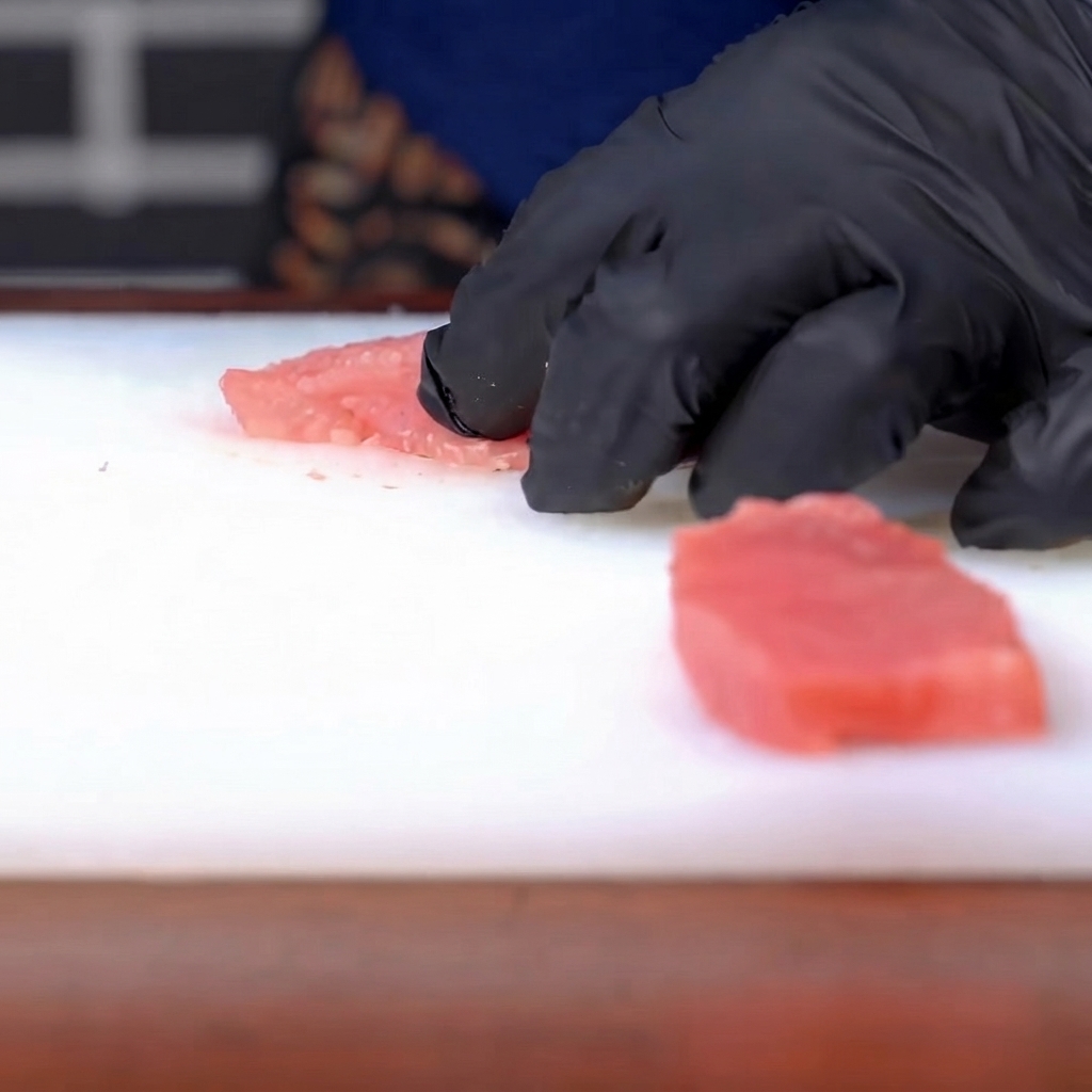 Sal y pimienta siendo espolvoreadas sobre una chuleta de cerdo cruda sazonada.