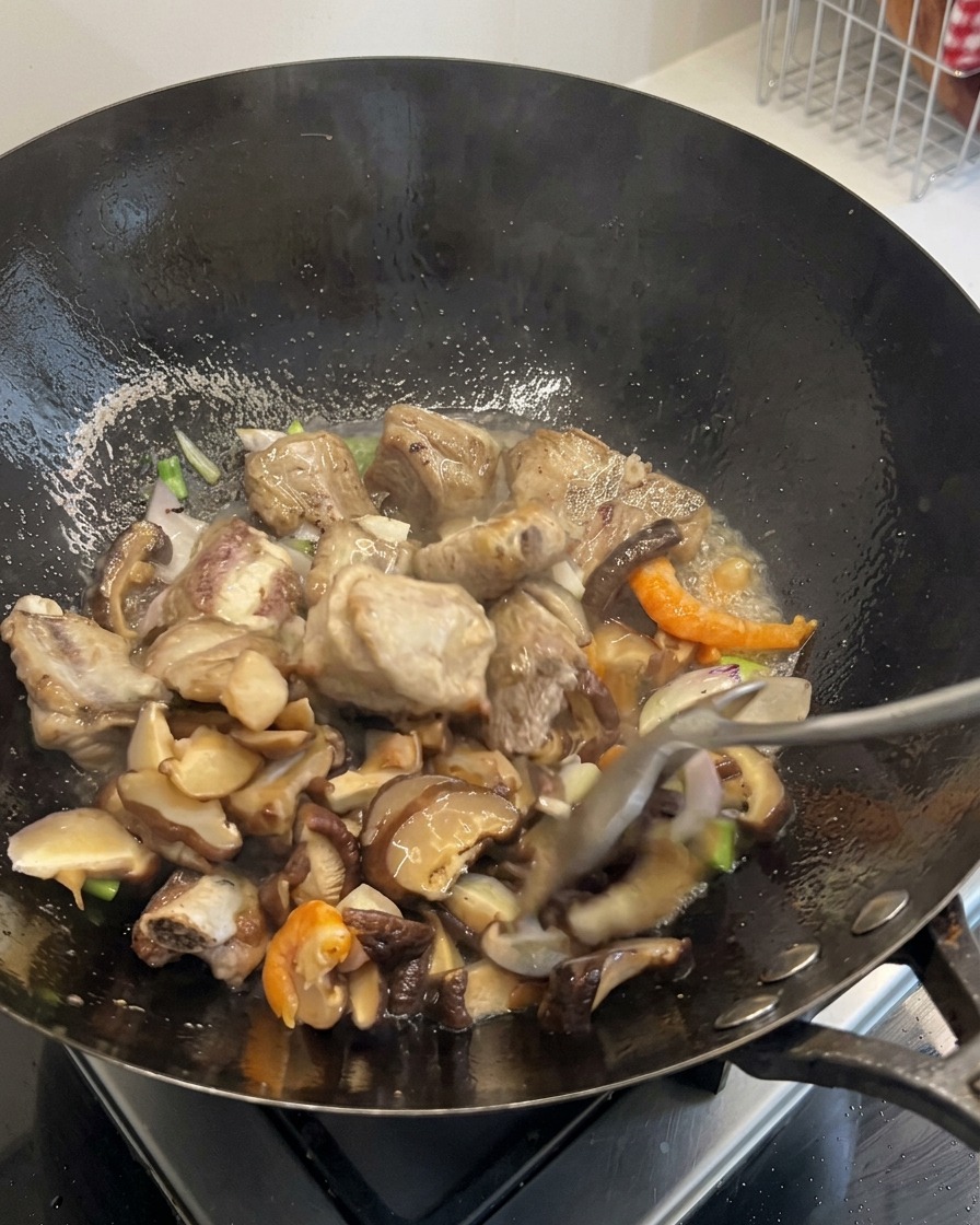Zanahorias en dados y granos de maíz siendo mezclados en el contenido chispeante del wok.