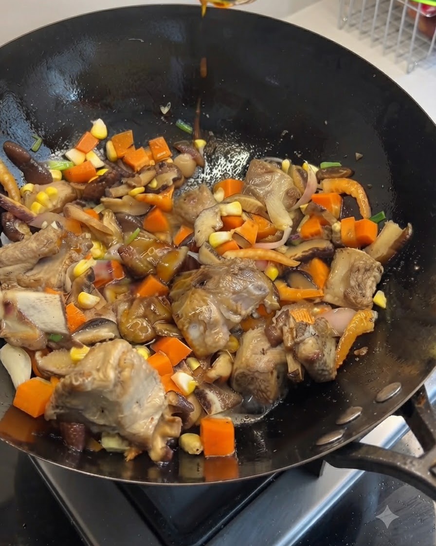 Salsas de soja oscura y clara siendo vertidas desde arriba en un wok lleno de costillas de cerdo, zanahorias, champiñones y maíz.