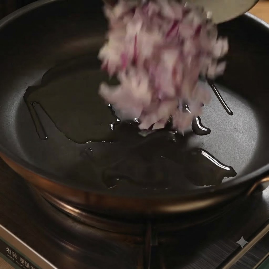 Cebollas rojas picadas echándose a una sartén con aceite.