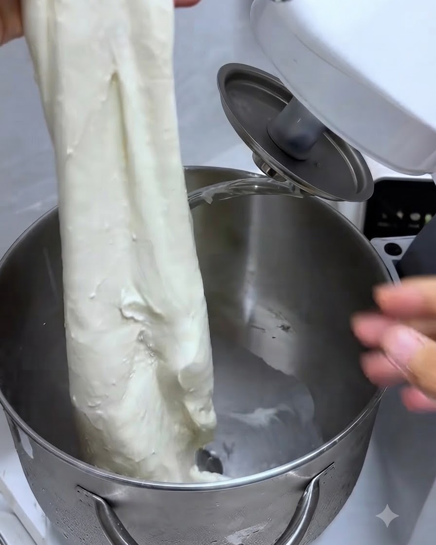 Estiramiento de un trozo de masa mostrando una membrana resistente y elástica en forma de guante.