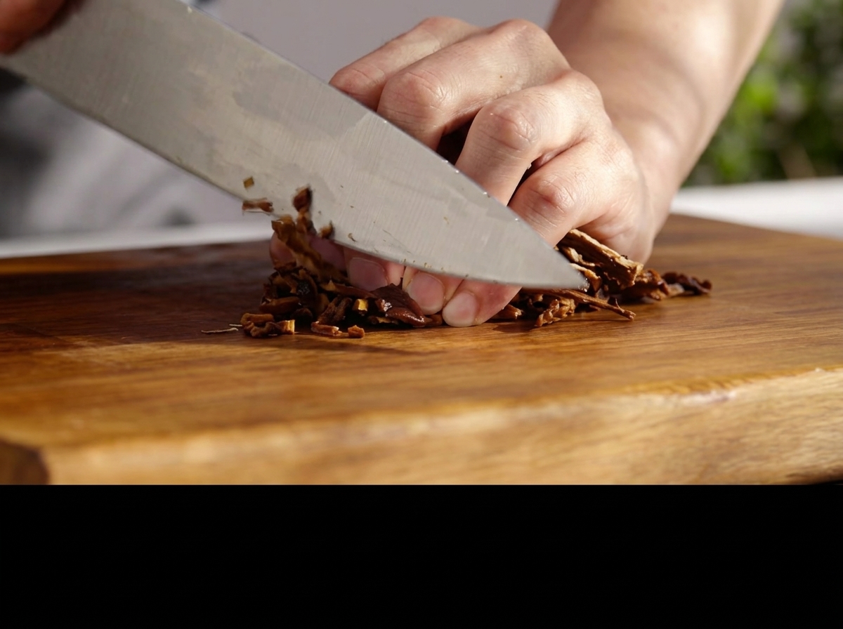 Un cuchillo picando finamente hongos rehidratados en una tabla de madera.