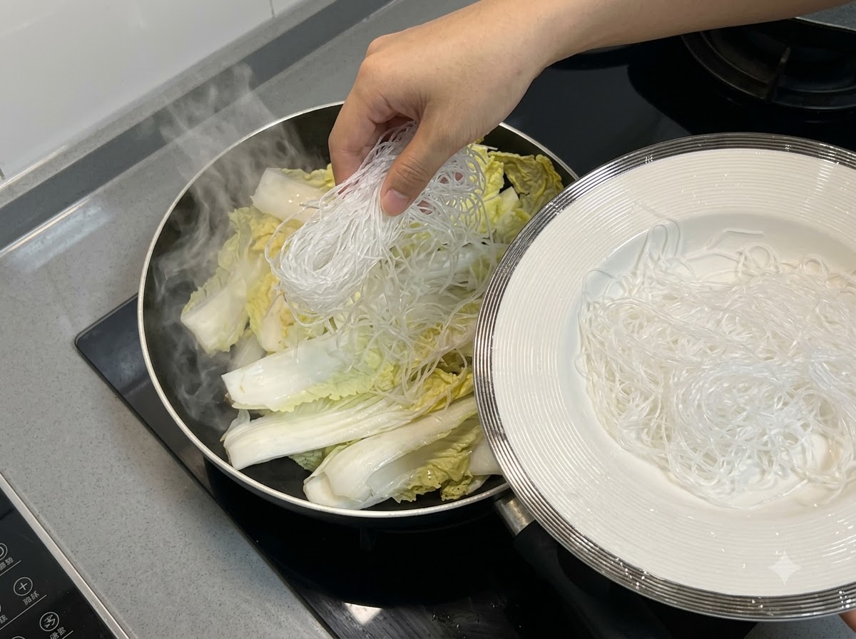 Fideos de arroz colocados sobre la col china dentro de la sartén.