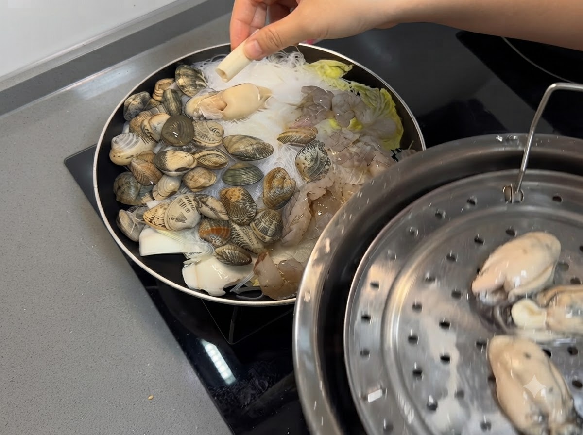 Camarones y ostras frescas colocados sobre la mezcla de mariscos y fideos en la sartén.