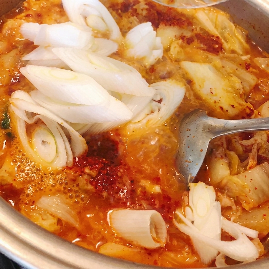 Rodajas de puerro siendo agregadas a la olla y revueltas con el estofado.