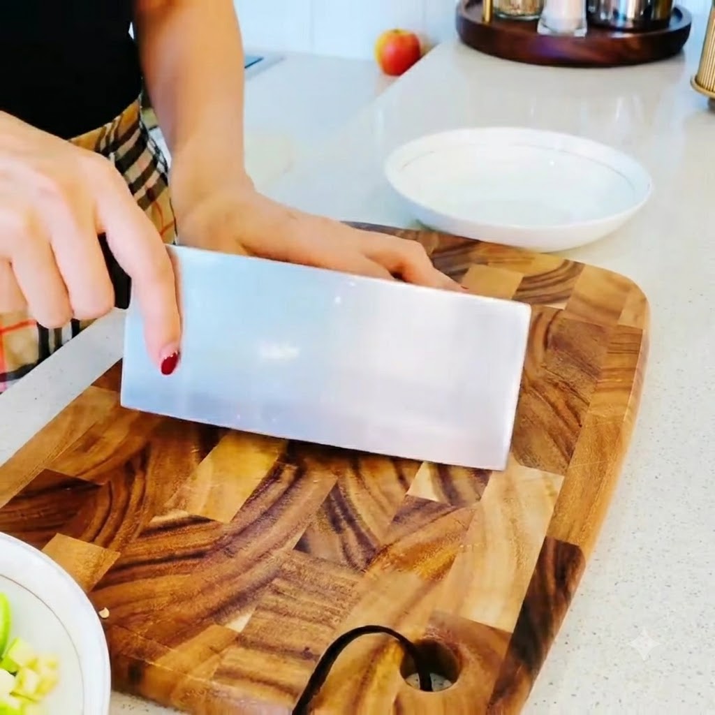 Setas enoki teniendo sus extremos de raíz cortados limpiamente sobre una tabla de cortar de madera.