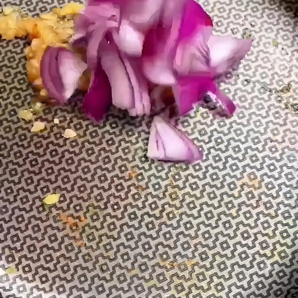Trozos de cebolla roja picada agregándose al ajo picado en una sartén con patrones.