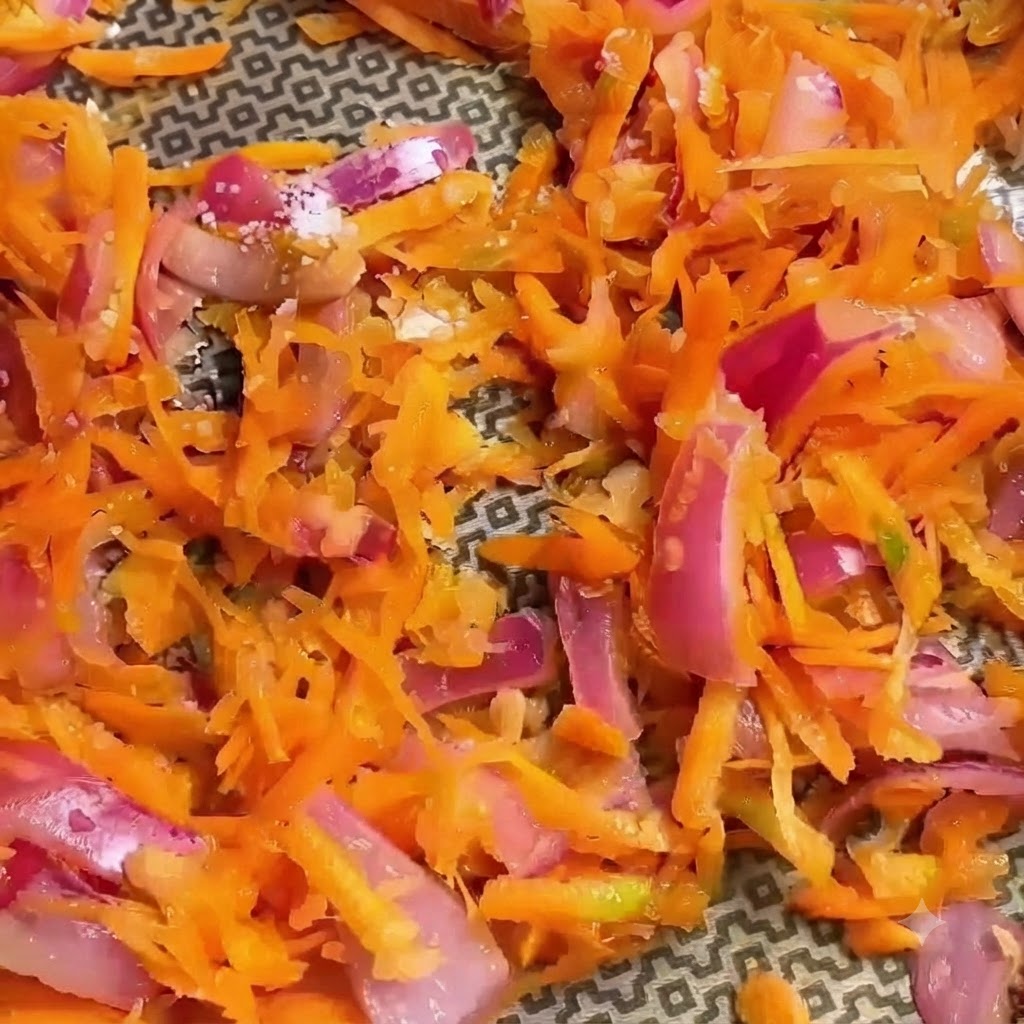 Primer plano de verduras ralladas sazonadas con especias visibles espolvoreadas encima.