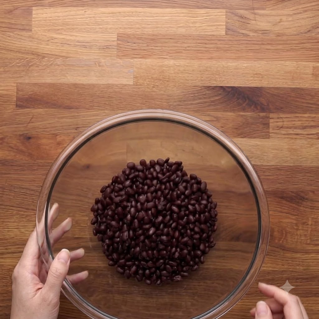 Frijoles negros enjuagados y escurridos dentro de un tazón grande de vidrio sobre una superficie de madera.